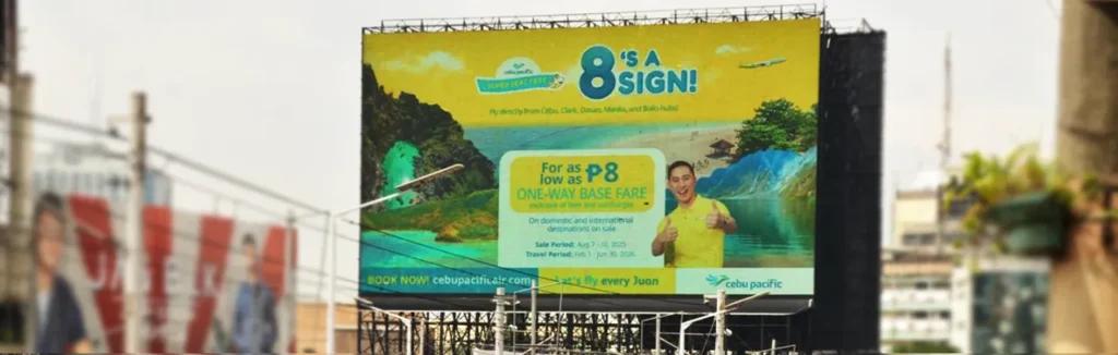 An ad promoting a P8 One-Way Base Fare seat sale with the tagline "8'S A SIGN!" featuring a man giving a thumbs-up against a tropical background.